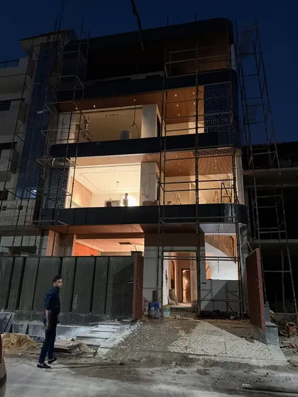 This shot shows the full front elevation of the modern Noida home, with its large windows and cantilevered balconies still surrounded by scaffolding.