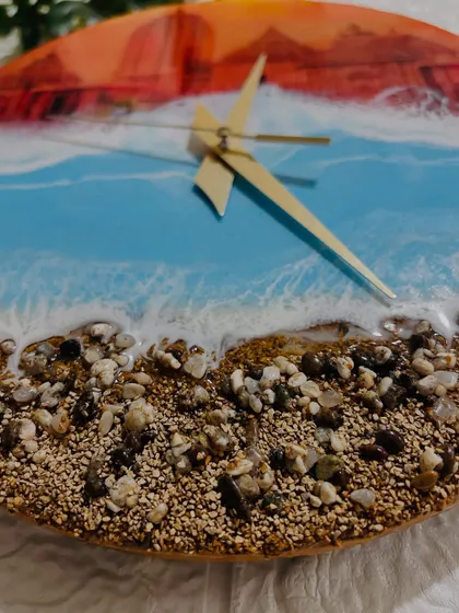 A close-up of the real sand and pebbles on the Jagannath Puri clock, creating a textured shoreline where the resin waves meet the land.