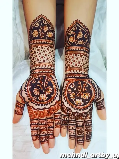 This design features a large, circular mandala on the palm filled with delicate floral vines. The pattern on the forearms uses a 'jaali' or net effect, creating a beautiful contrast in textures.