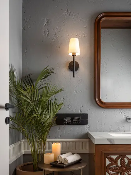 This powder room is all about understated elegance. A textured grey wall adds depth, while the warm wooden mirror and carved vanity bring a touch of luxury. The sleek black fixtures keep it modern.