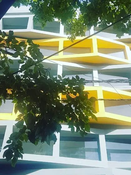 A work-in-progress view of the commercial building in Indiranagar. The staggering planes and bold use of color are key elements of the elevation design, seen here through the foliage of a nearby tree.