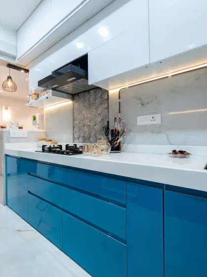 A closer look at the high-gloss blue acrylic cabinets and the textured 3D tile backsplash. The under-cabinet LED lighting not only illuminates the workspace but also highlights the different textures in the design.