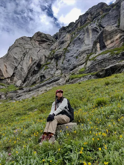 Taking a moment to soak it all in. The meadows on the Hampta Pass trek are filled with yellow wildflowers, set against dramatic rock faces.