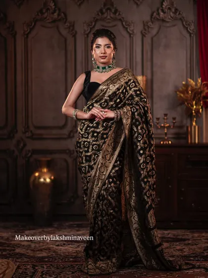 A full-length shot showcasing the beautiful drape of the black and gold saree and the overall elegant posture.