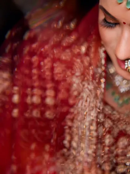An intimate, top-down shot of the bride, focusing on her elaborate eye makeup and nose ring. The motion blur of her lehenga adds a dynamic feel.