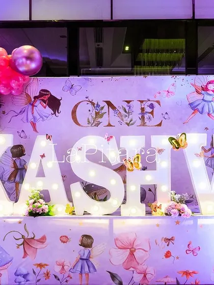 Large marquee letters spelling 'KASHVI' for a first birthday, set against a backdrop of fairies and butterflies.