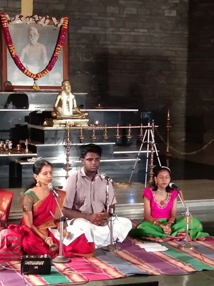 A focused shot of the students during their Ramananjali Sangeetham offering. The setting at the Ramana Shrine adds a deep spiritual dimension to their performance.