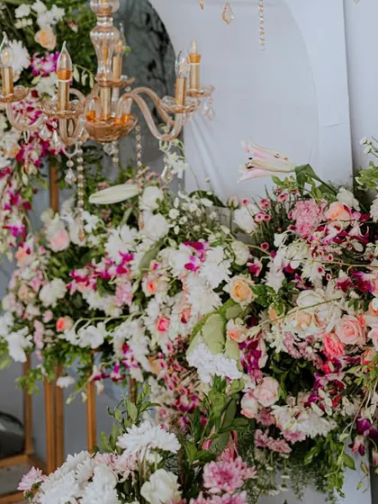 A close-up of a lush floral arrangement featuring a mix of pastel flowers and a small, elegant chandelier.