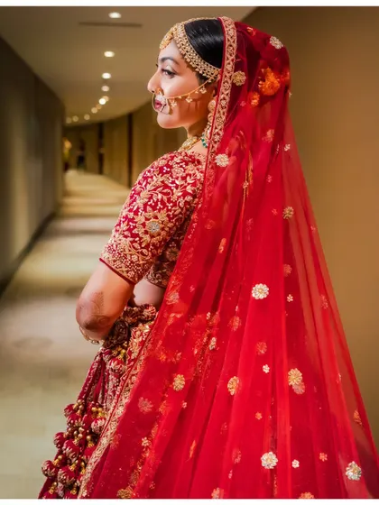 A side profile of the bride, highlighting the elegant drape of her veil and the intricate embroidery on her lehenga.