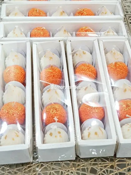 A close-up of my laddoo and modak candle gift sets, neatly packed and ready for dispatch. The clear packaging showcases the intricate details of each candle.