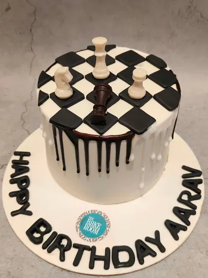 A clever chess-themed cake for a birthday. The design features a chessboard top with edible chess pieces and a chocolate drip, making it a perfect checkmate for any chess lover.