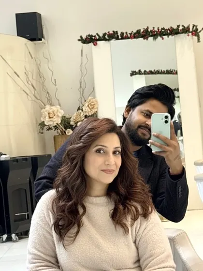 A selfie with a happy client, showing off her new chestnut brown curls. It's a soft, glossy, and timeless look that radiates warmth.