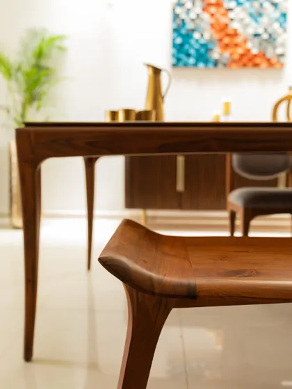 This dining set from Alankaram showcases exquisite craftsmanship. The elegantly curved legs of the bench and table are a beautiful example of contemporary Indian furniture design.