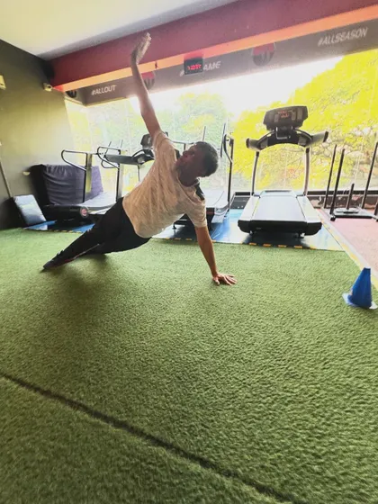 A client holds a side plank with an arm reach, a dynamic variation that challenges oblique and shoulder stability.