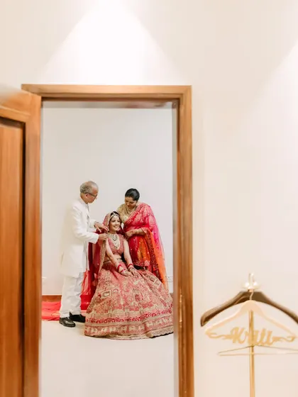 A touching moment captured through a doorway, as the bride's parents give her their blessings before the ceremony.