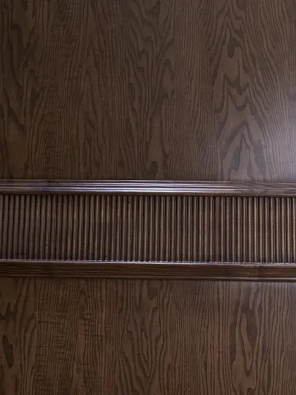 A detail shot of the fluted band on the ash wood door, showcasing the precision of the CNC carving.