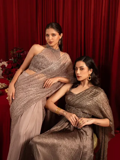 A sophisticated dual-model pose for a contemporary ethnic wear brand. The composition highlights the different styles of the sarees in a cohesive, elegant frame.