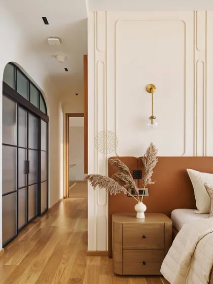 The master bedroom has an open flow into the home office, separated by arched sliding doors with frosted glass. The wood flooring continues throughout, unifying the two spaces.