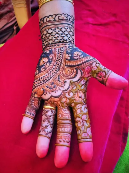 A bold party design using the reverse-fill technique. The dark background makes the floral patterns on the fingers and the cuff stand out dramatically.
