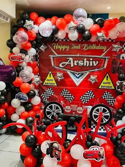An elaborate Disney "Cars" theme for a 2nd birthday. The balloon arrangement in red, black, and white mimics a racetrack, complete with character cutouts and checkered flags.