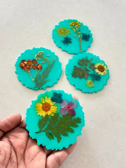 A beautiful set of handmade coasters with pressed flowers preserved in turquoise resin, available for purchase or to make yourself.