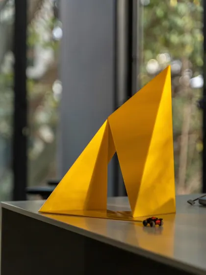 The "Yello" model on a desk, with toy cars for scale. This playful photo shows how we test and refine our ideas, moving from digital design to physical models to ensure the final, 30-foot-tall installation is perfectly executed.