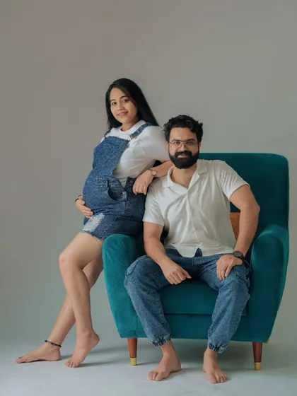 A cool and casual couple's portrait. The denim dungarees and relaxed pose on the armchair give this studio shot a modern and laid-back vibe.