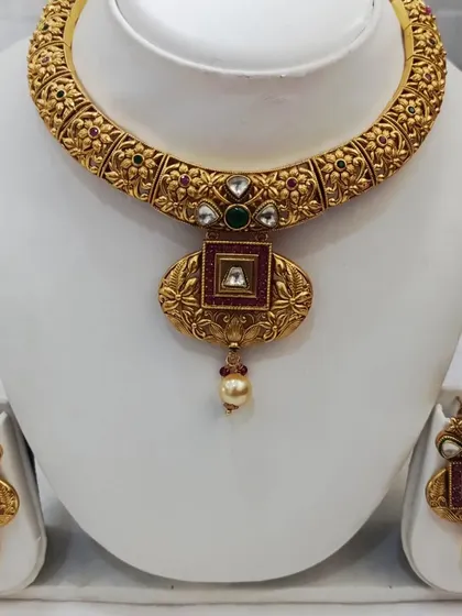 A beautiful antique choker with a square pendant. The intricate floral carving on the band and the ruby-colored center stone give it a very royal feel.
