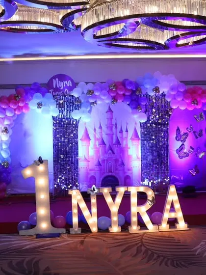A full view of Nyra's princess-themed first birthday stage, showcasing the grand scale and beautiful purple lighting.
