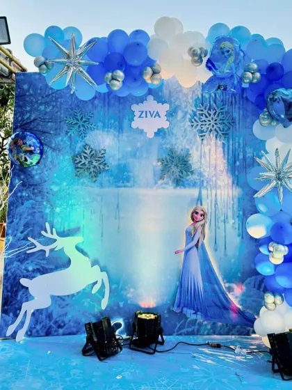 A winter wonderland comes to life with this Frozen-themed backdrop. Featuring Elsa against an icy landscape and surrounded by a blue and white balloon arch, it's the perfect spot for birthday photos.