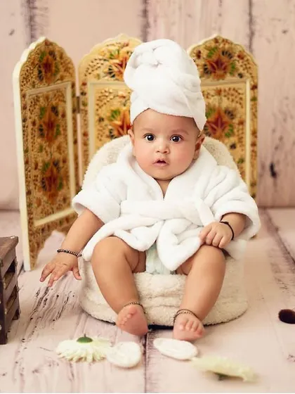 This little one is awake and enjoying the spa treatment. The ornate screen in the background adds a touch of elegance to the setup.