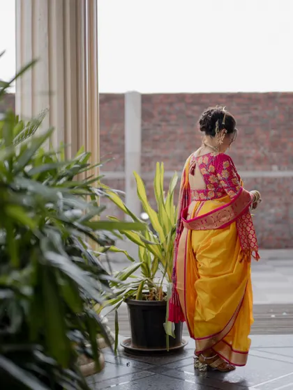 A candid shot of the bride from the side, showing the details of her hairstyle and the back of her blouse.