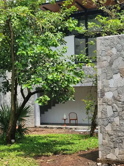 A quiet corner of the Villa in the Grove, where a stone wall provides privacy and a sense of enclosure. The bedrooms above are like lanterns suspended in the trees, designed to glow at night.