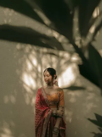 An artistic portrait with the bride partially obscured by a large leaf's shadow, creating a moody and intriguing image.