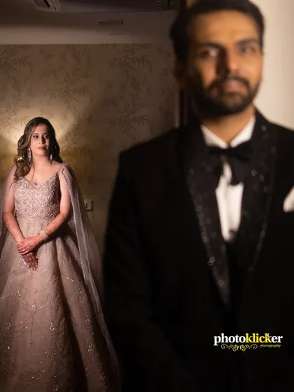 An artistic portrait from a ring ceremony, with the groom in sharp focus and the bride elegantly standing in the softly lit background.