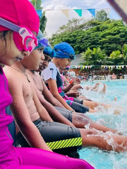 The simple joy of making a splash! Young swimmers in our Learn to Swim program have fun kicking at the edge of the pool, an essential drill for building leg strength and getting comfortable with the water.