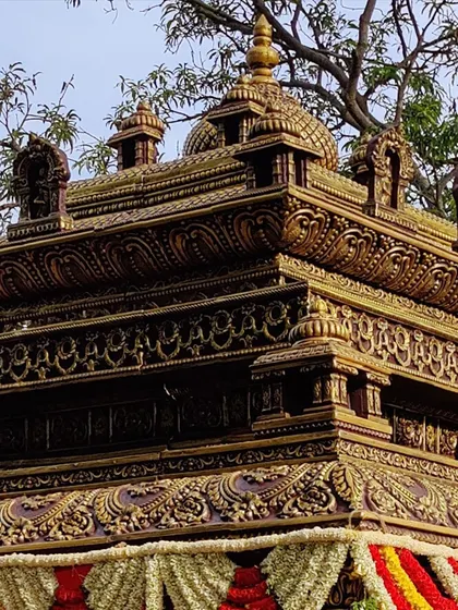 An upward view of the ornate gopuram of a wedding mandap, showcasing the detailed carving and traditional architecture that defines our temple-style setups.