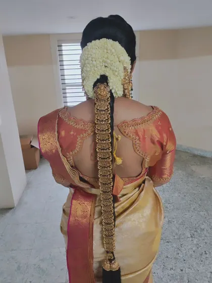 A clean and classic South Indian bridal braid with a full gold 'Jadai' set, showcasing how the hairstyle complements the rich texture of the silk saree.