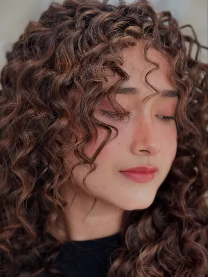 A detailed shot of the curl pattern. When cut correctly, curly hair can frame the face in a soft, beautiful way.
