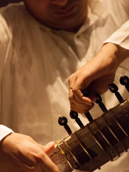 A close-up shot, tuning the sitar before a performance. The preparation is as much a part of the music as the performance itself.