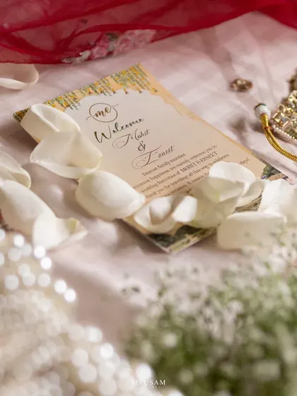 A beautiful flatlay of the wedding invitation, surrounded by rose petals and pearls. This shot captures the first chapter of the couple's story and the elegant details of their day.