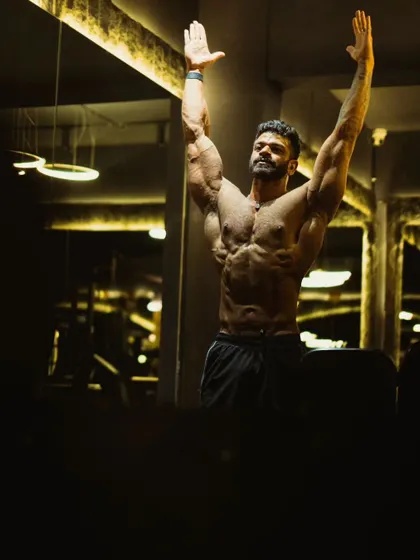 Arms raised in a victory pose, showcasing the full expanse of the chest and the definition in the arms and shoulders.