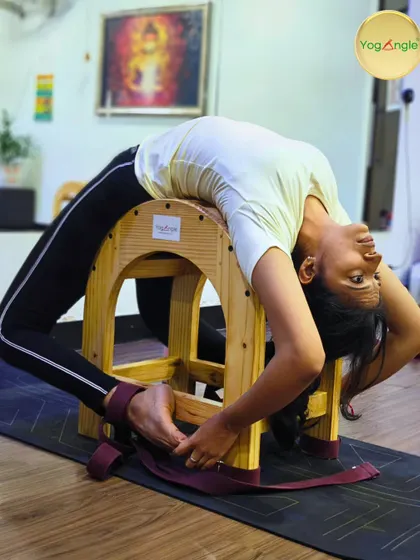 A student demonstrates a deep backbend on the tall backbender. This advanced prop provides full spinal support, allowing for a safe and expansive heart opening experience in Viparita Dhanurasana, building both courage and calm.