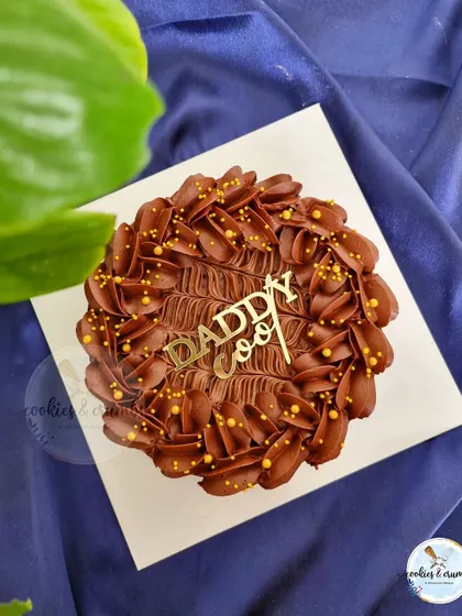A "Daddy Cool" brownie cake. This rich chocolate brownie is topped with piped chocolate frosting and gold sprinkles for a simple but delicious treat.