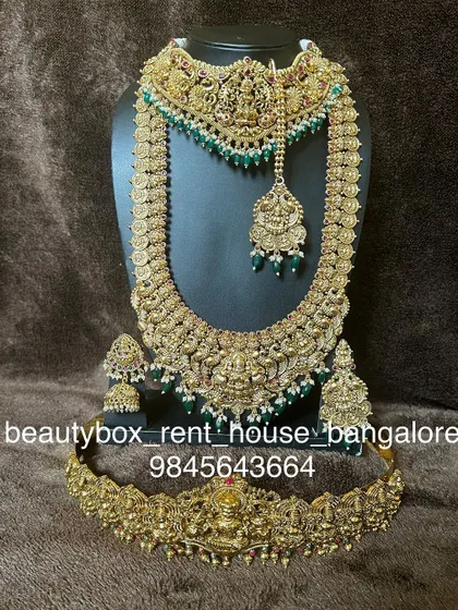This is a grand bridal set with green beads and antique finish. The rental includes a choker with a maang tikka attached, a long haaram, and a temple vaddanam.