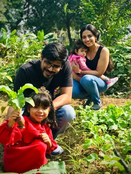 A beautiful family photo amidst the vegetable patches. The daughter proudly holds up her harvest, a perfect memory of their farm day out.