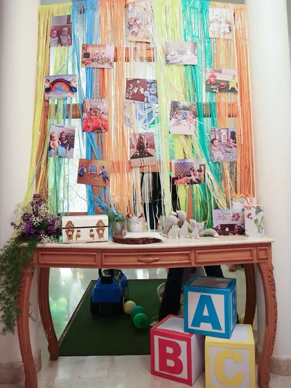 A memory wall created with colorful yarn and photos from the twins' first year, set above a vintage-style console table with classic "ABC" blocks.