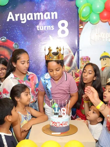 Family and friends gather to celebrate an 8th birthday with a Roblox-themed party, complete with colorful balloons and a custom cake.