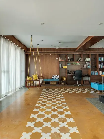 This wider view of the library shows the open-plan design and the use of Jaisalmer stone flooring with patterned tile inlays. This multi-functional space seamlessly integrates areas for work, reading, and family time.