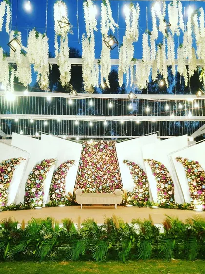 This is the same modern outdoor stage viewed from a straight-on angle, emphasizing the symmetry and scale of the design. The lush greenery at the base of the stage provides a natural finish.